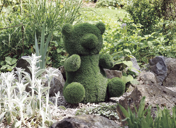 Garden plush in artificial turf, decorative and ingenious. Sitting bear figurine